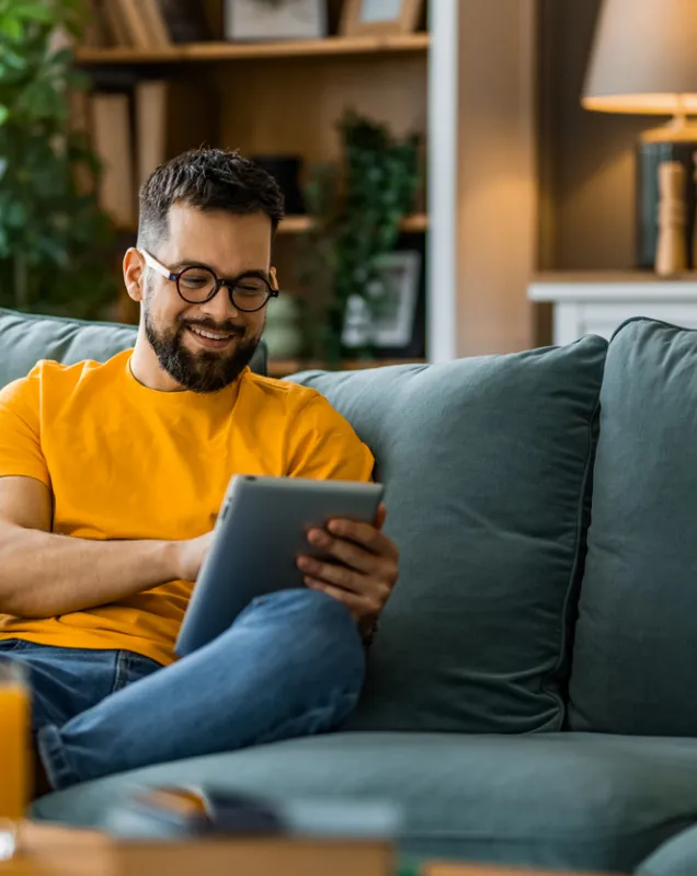 Jeune homme lisant sur une tablette assis sur un canapé